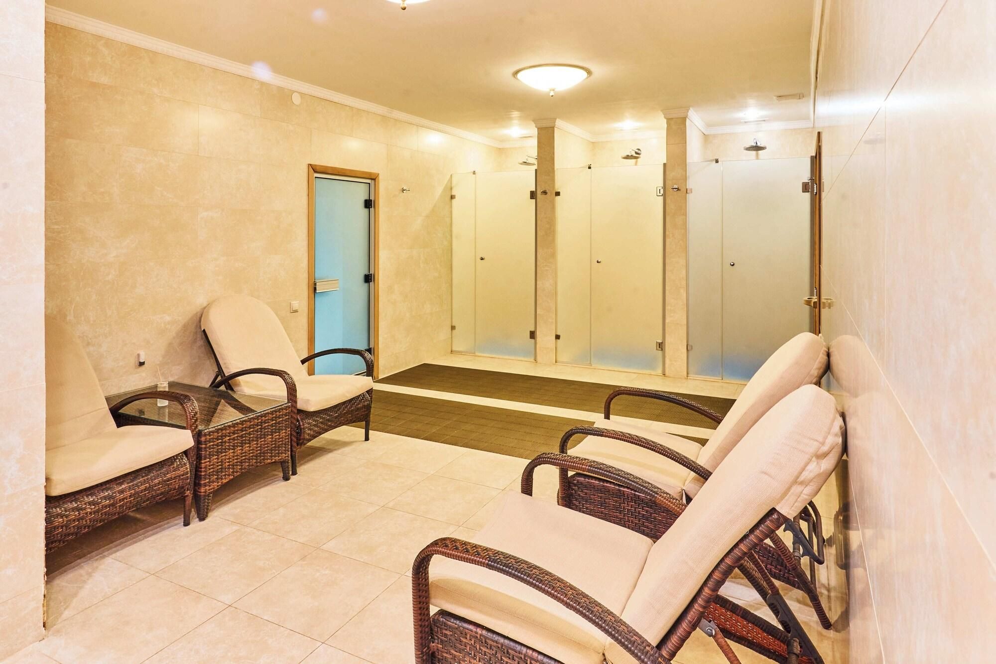 Un espacio de spa con sillas de mimbre, una puerta azul y un box de ducha de cristal.
