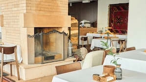 Um restaurante acolhedor com lareira de tijolos, cadeiras e mesas de madeira preparadas para refeições.