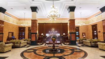 A lobby with a grand chandelier, a reception desk, and multiple seating areas.