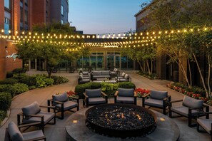 An outdoor seating area with a fire pit, surrounded by chairs and tables, under string lights. - Courtyard by Marriott Columbus OSU (Columbus)
