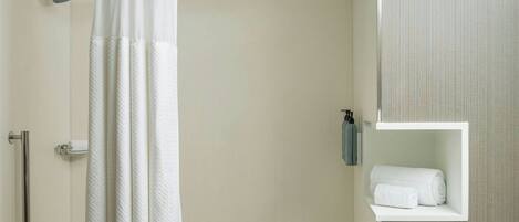 Un baño moderno con bañera, cortina de ducha, toallero y un estante pequeño con una toalla.