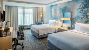 Une chambre d’hôtel avec deux lits, un bureau avec un ordinateur, une chaise et une grande fenêtre avec des rideaux.