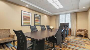 A conference room with a long table, black chairs, a sofa, and two framed artworks on the wall.
