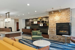Un vestíbulo moderno con mostrador de recepción, zona de estar, chimenea y un muro decorativo.