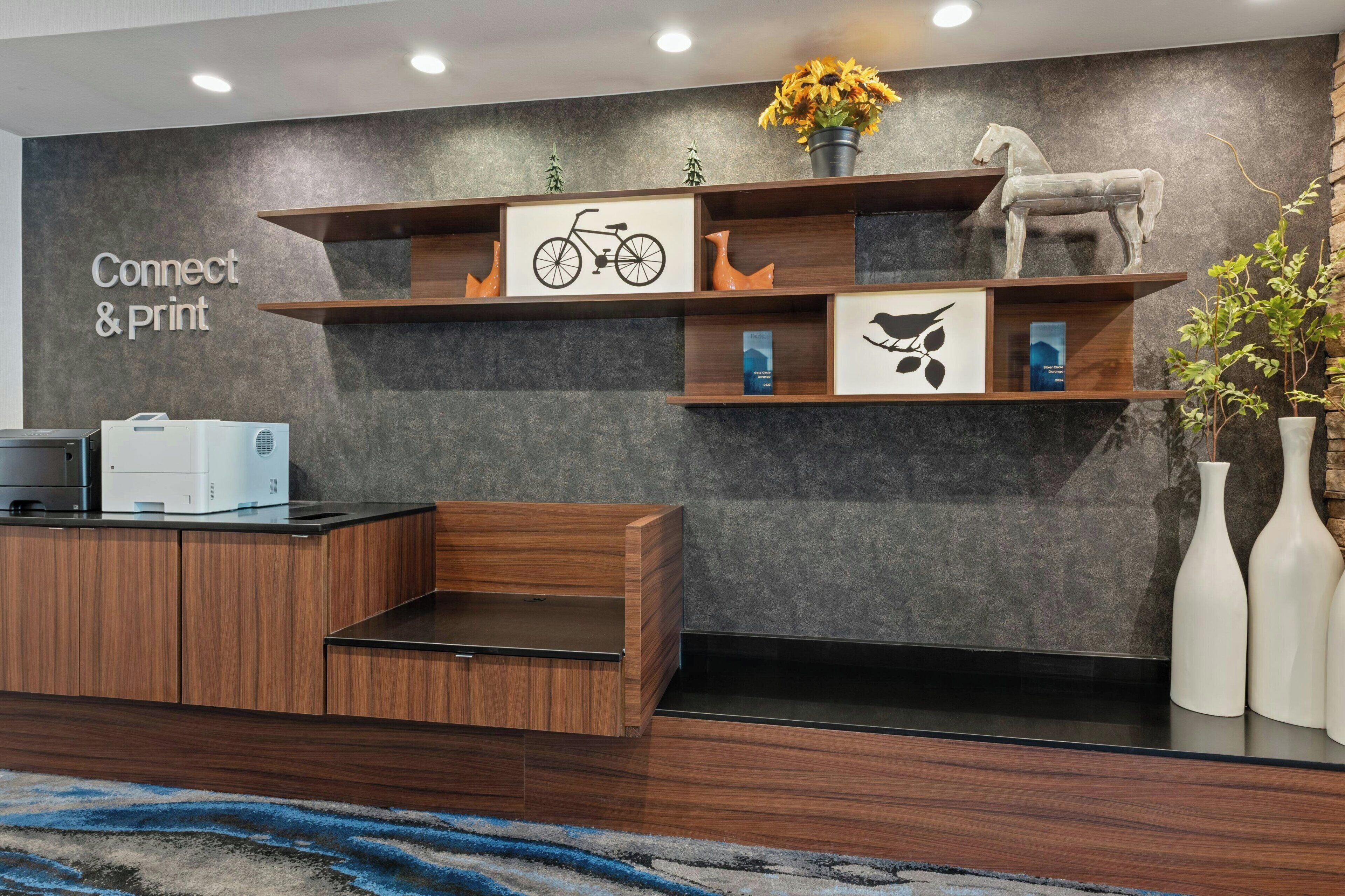 A reception area with a 'Connect & Print' sign, a bicycle illustration, a horse sculpture, and a plant.