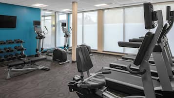 A gym with treadmills, dumbbells, and exercise equipment.