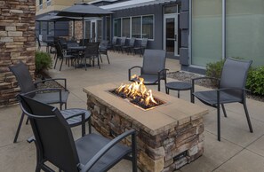 An outdoor patio with a fire feature, stone walls, and modern outdoor furniture. - Fairfield Inn & Suites by Marriott Geneva Finger Lakes (Geneva)