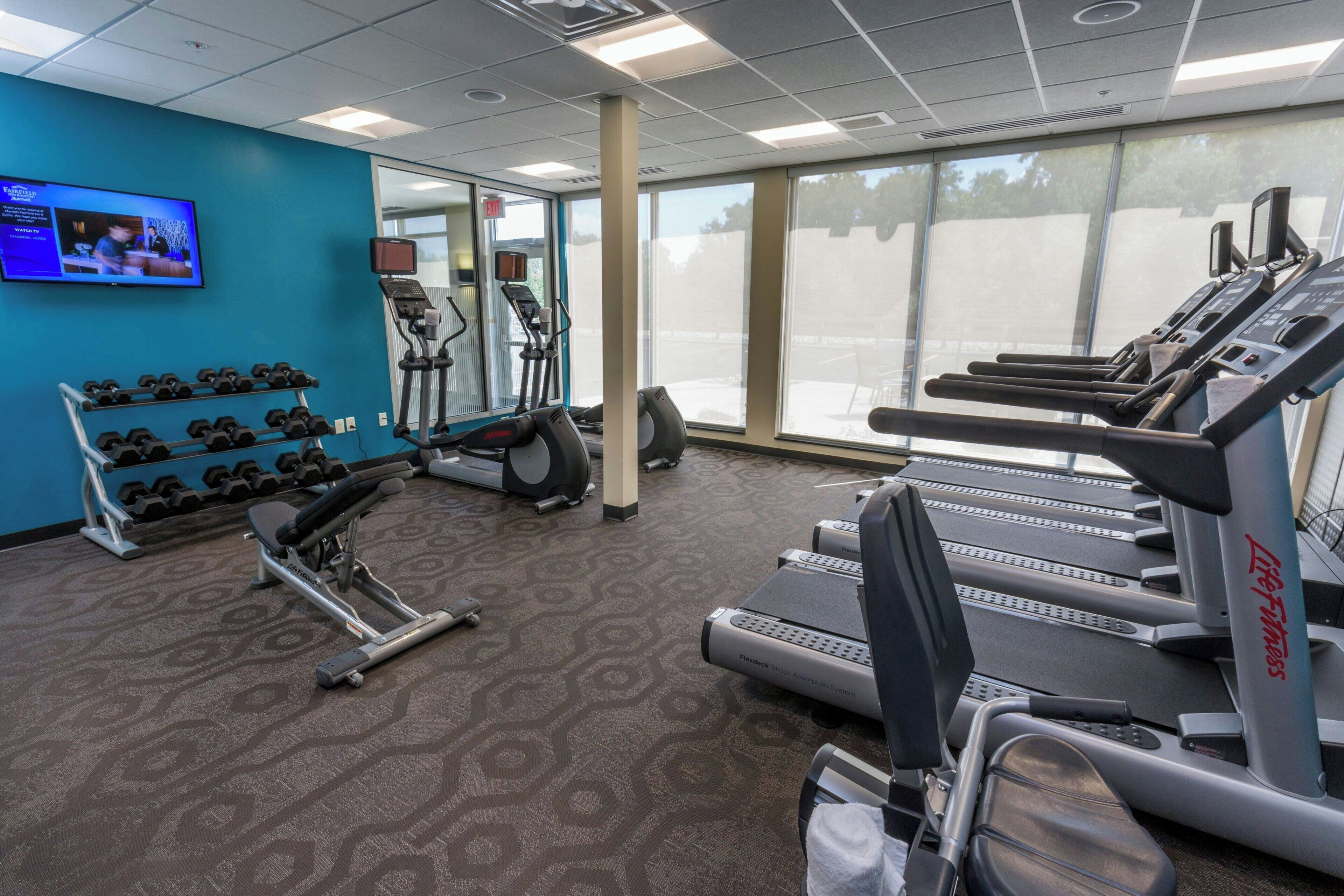 Un gimnasio con cintas de correr, mancuernas y equipo de ejercicio.