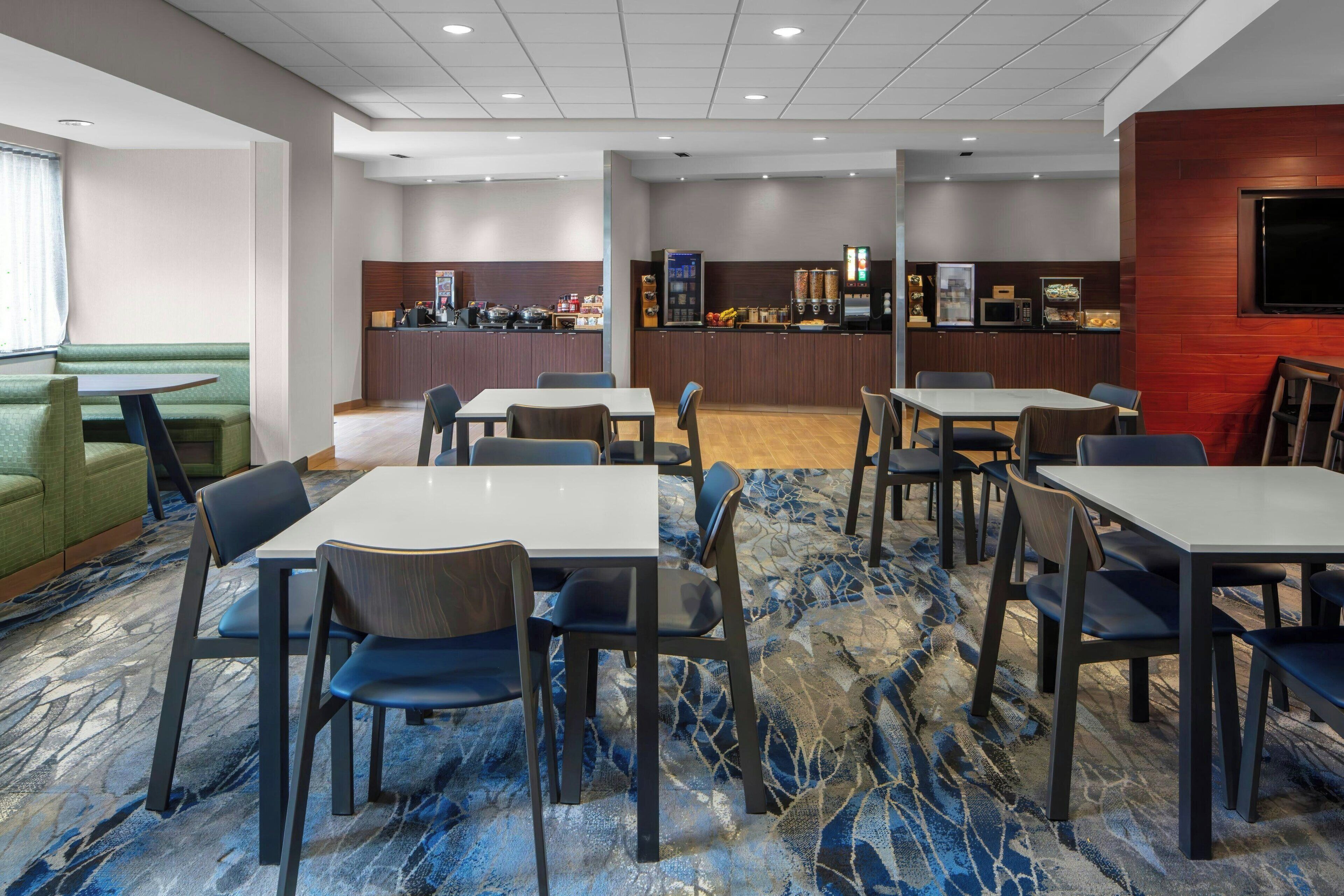 A hotel dining area with a bar, seating arrangements, and a patterned carpet.