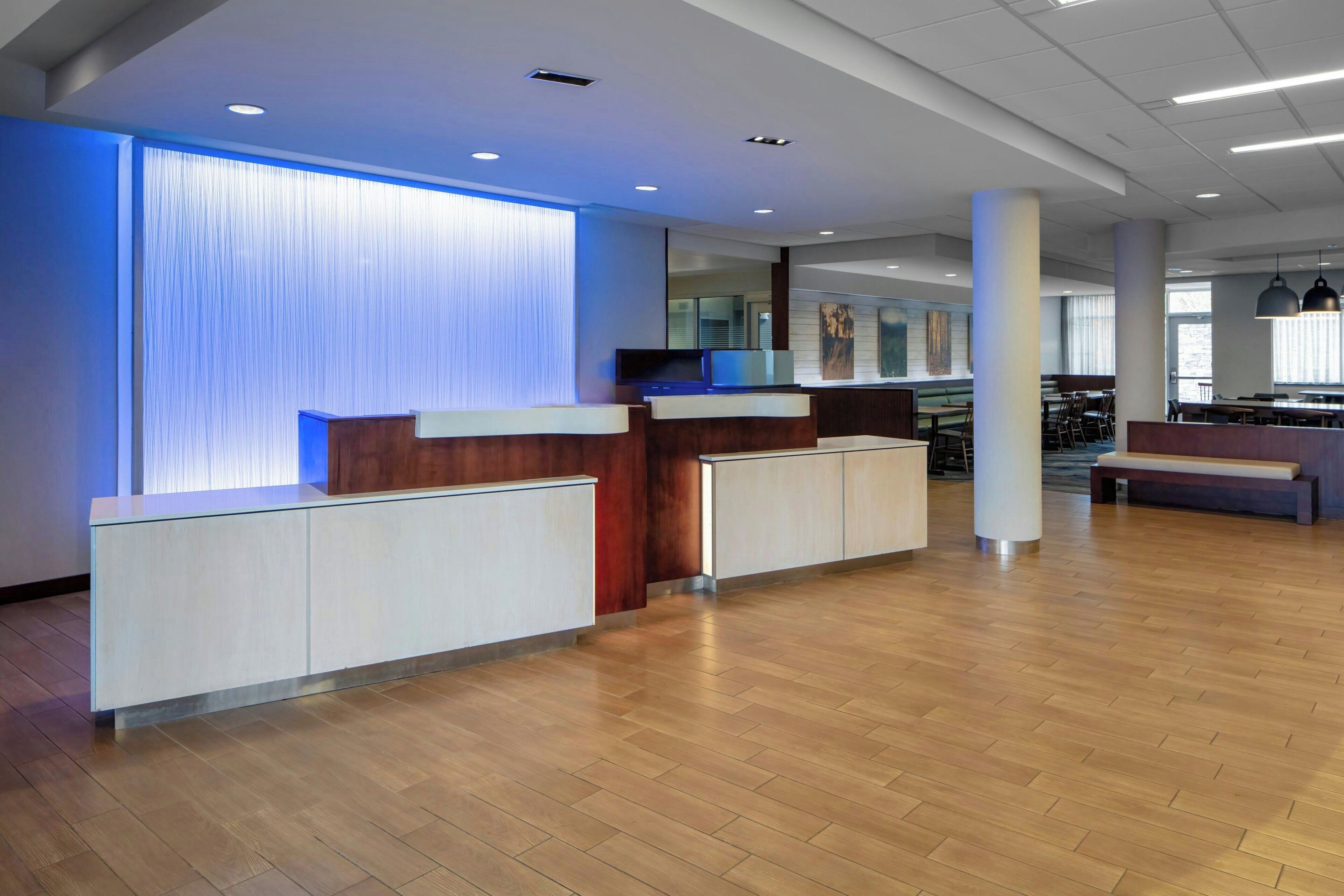 A modern reception area with a wooden reception desk, white cabinets, and a blue-lit wall.