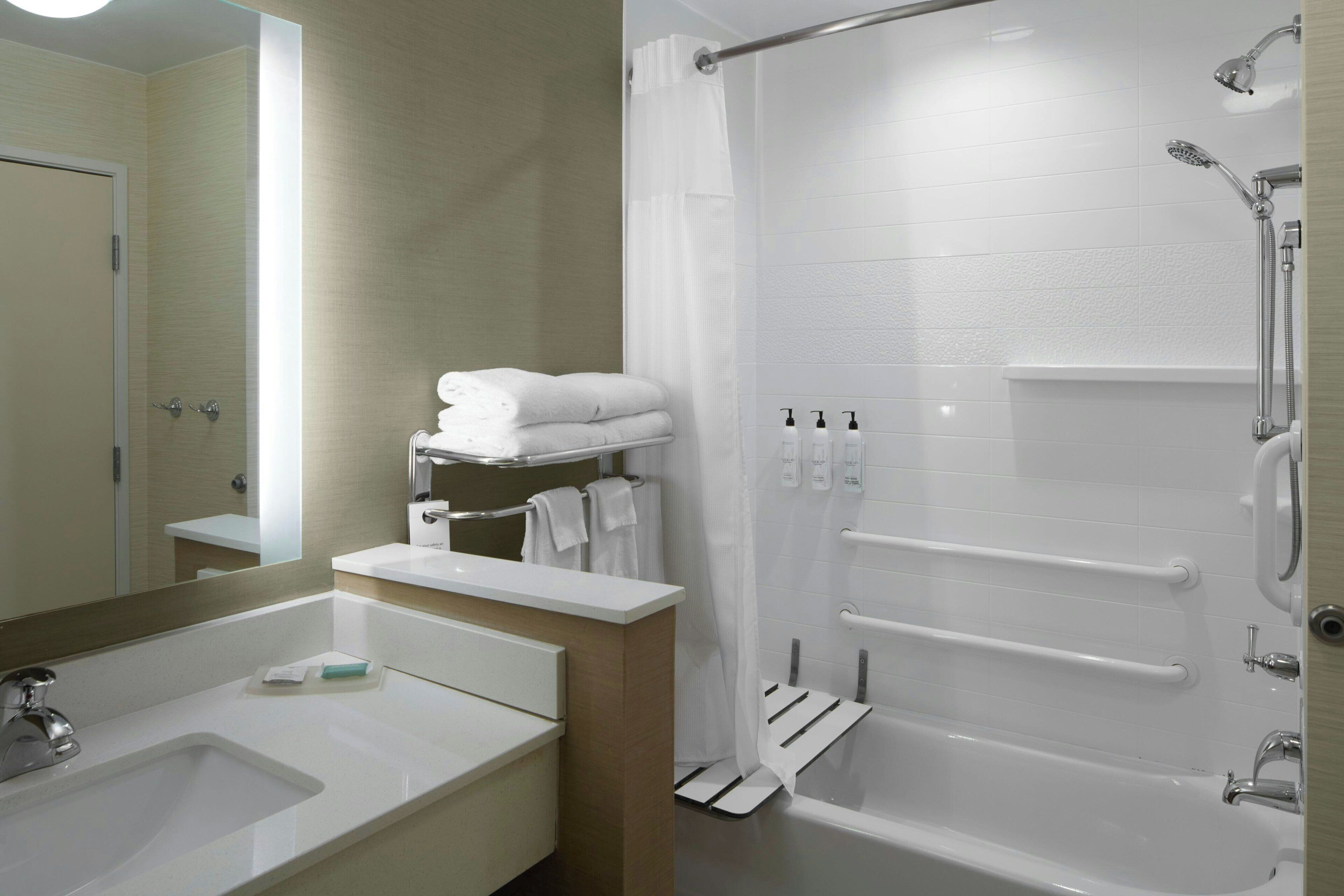 Ein modernes Badezimmer mit Waschbecken, Spiegel und Duschbereich.