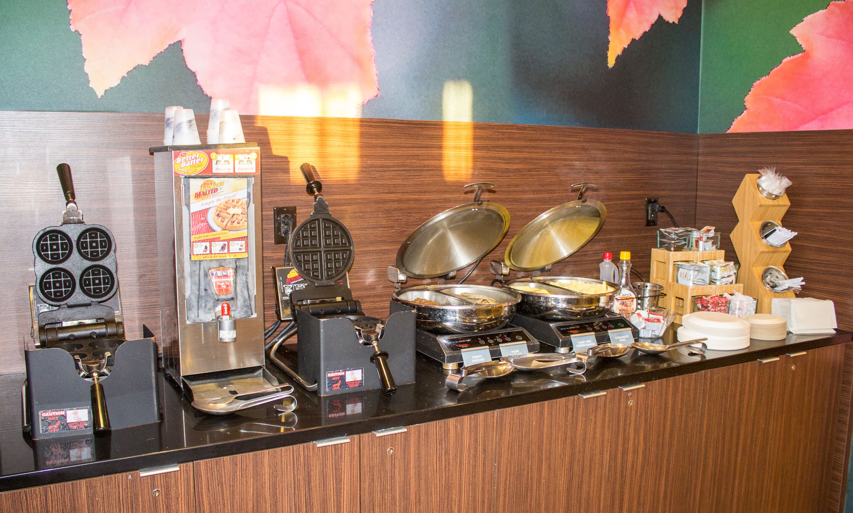 Un comptoir de buffet proposant divers plats et appareils, notamment une machine à gaufres et une machine à café.