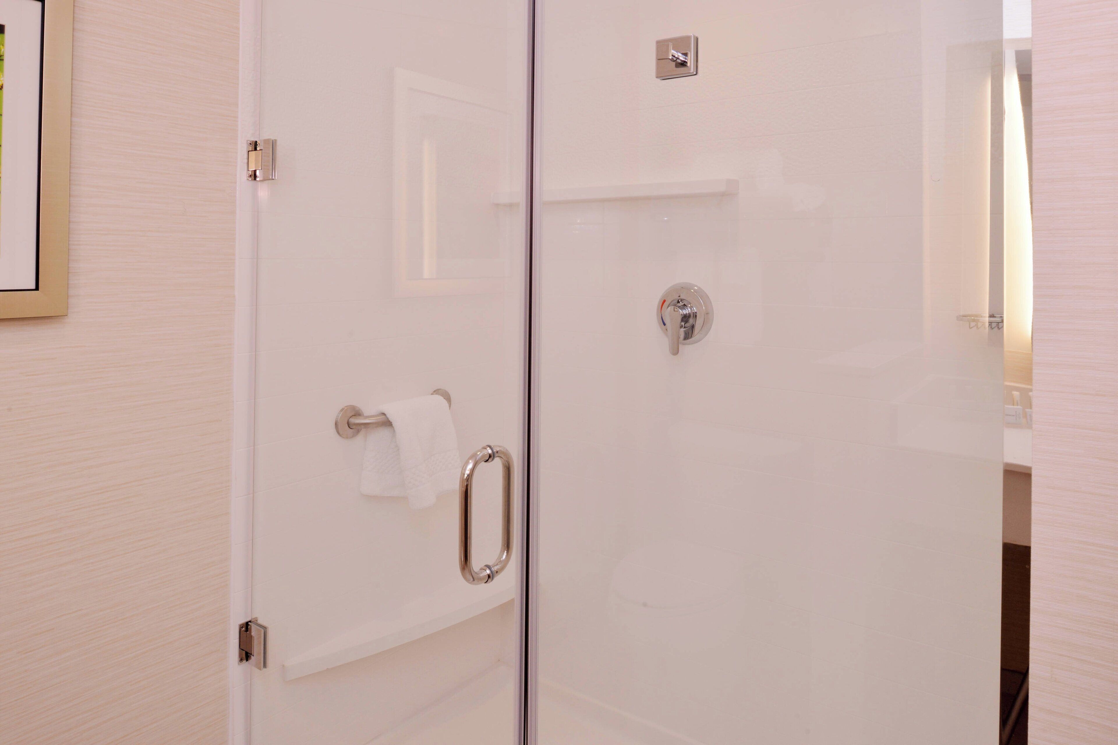A glass-enclosed shower with a towel rack and a showerhead.