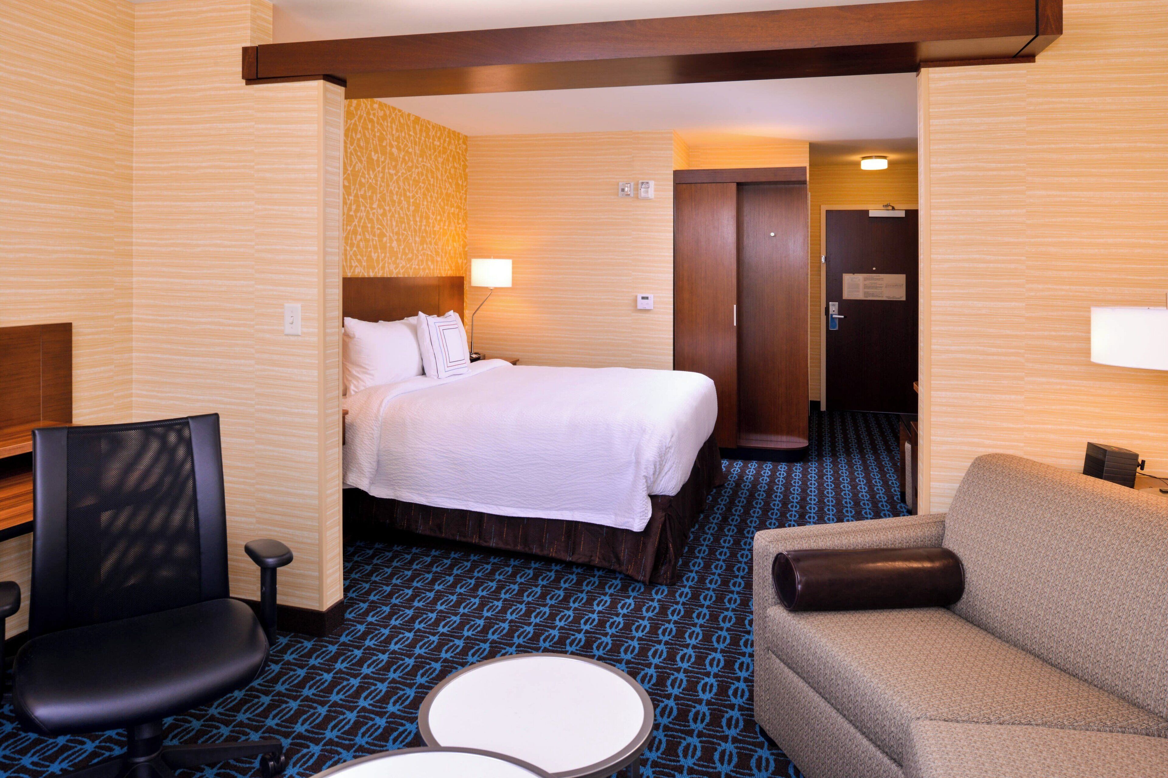 Une chambre d’hôtel avec un lit, une chaise, un canapé et une petite table.