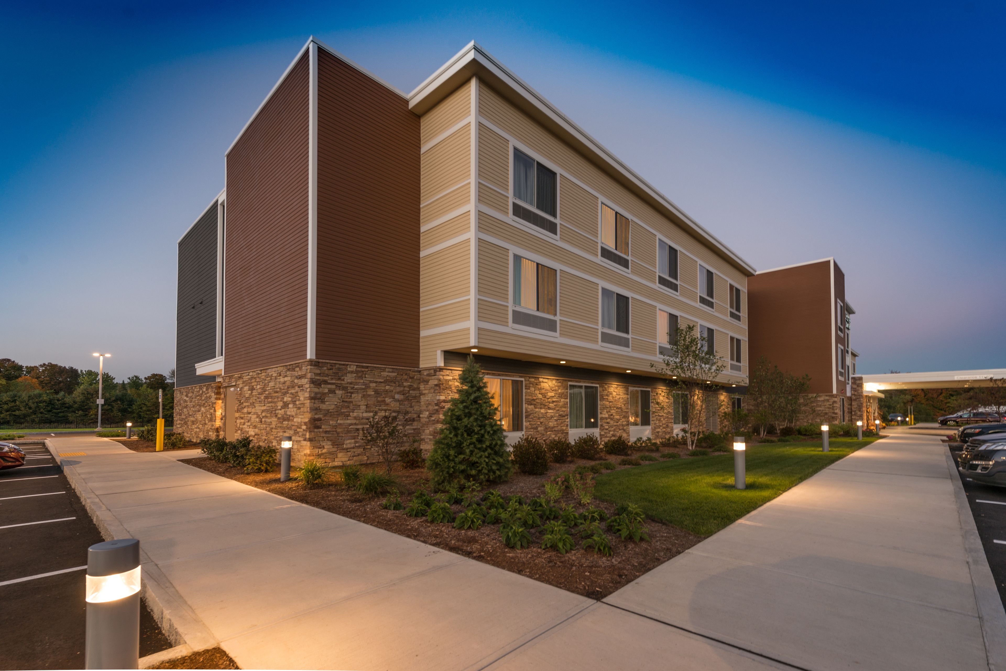 A multi-story hotel with a stone facade, multiple windows, and a parking lot.
