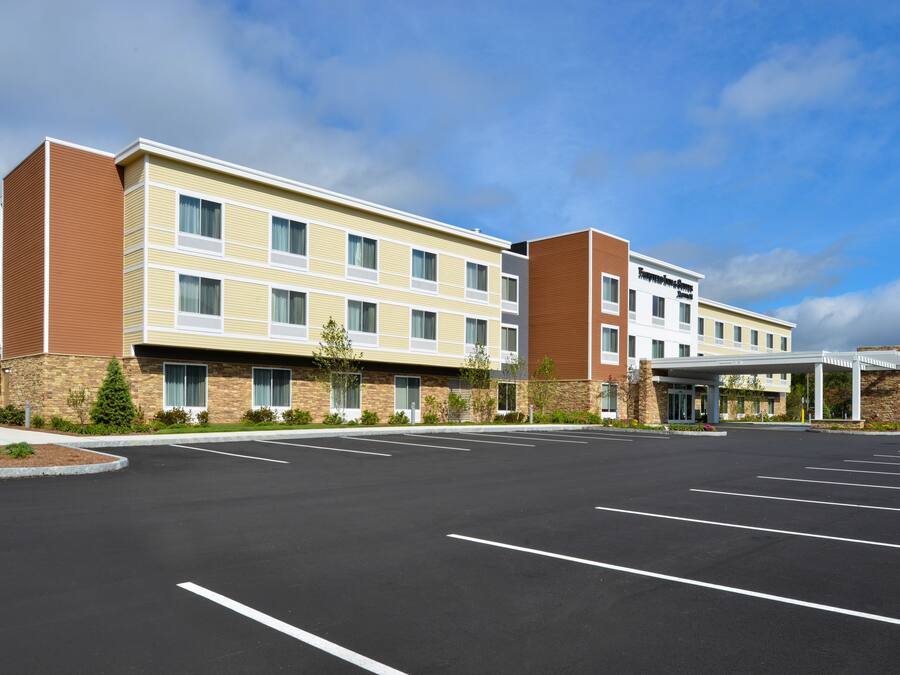 A multi-story hotel with a parking lot in front.