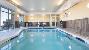 Une piscine à l’eau d’un bleu limpide, entourée de chaises et baignée de lumière.