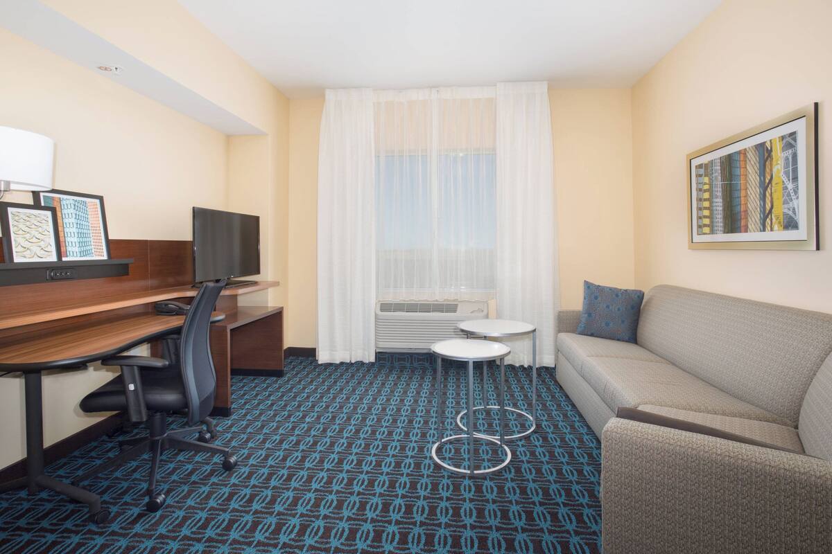 A hotel room with a desk, chair, sofa, and a small table.