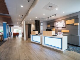 Un área de recepción moderna con mostrador, zona de estar y vistas al exterior.