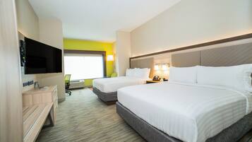 A hotel room with two beds, a flat-screen TV, a desk with a chair, and a window with a view.