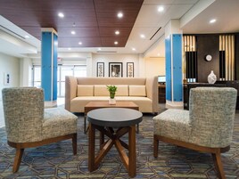 Un hall de hotel con un sofá, dos sillones, una mesa de centro y una recepción.