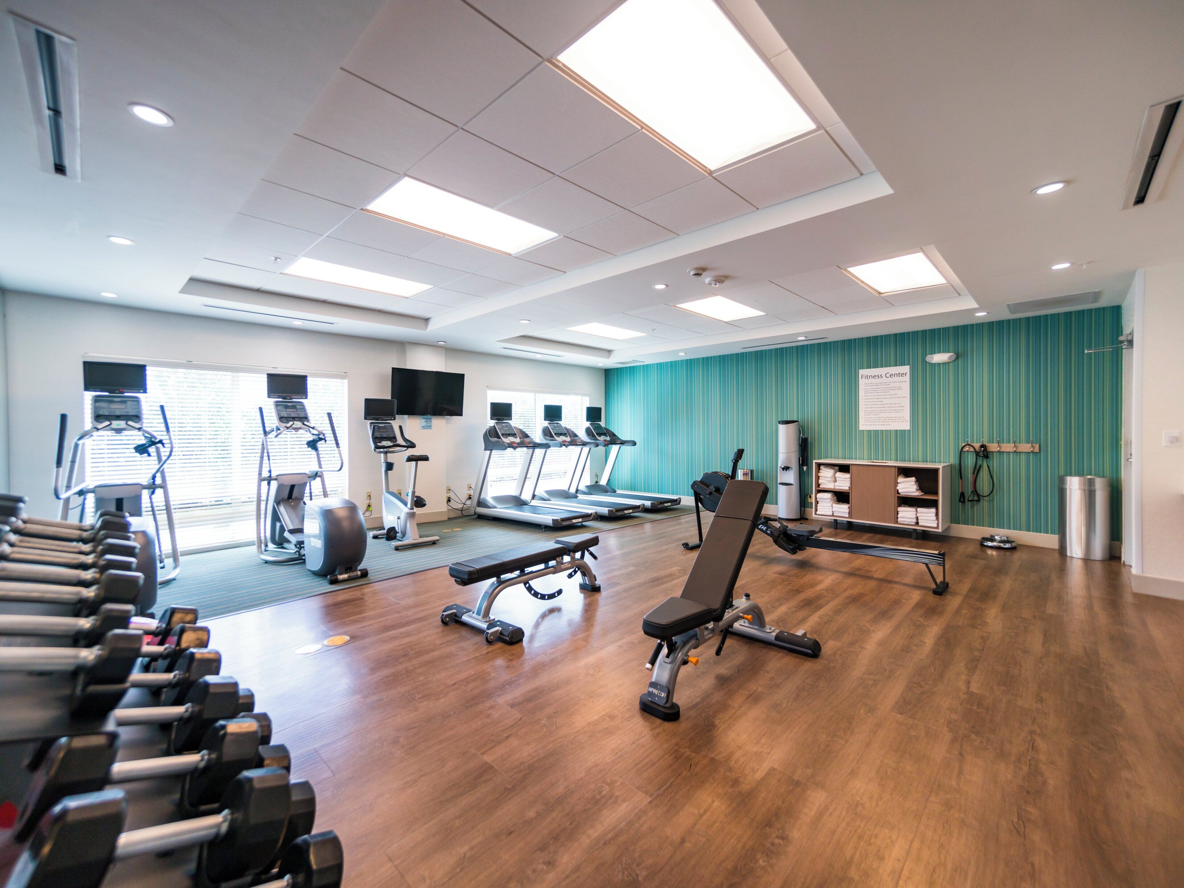 A fitness center with treadmills, elliptical machines, and free weights.