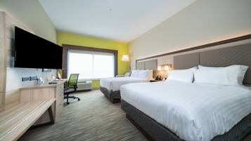Une chambre d’hôtel avec deux lits, un bureau, une chaise, un téléviseur à écran plat, une fenêtre et une lampe fixée au mur.