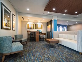 Un vestíbulo de hotel moderno con una zona de estar, un mostrador de recepción y una alfombra estampada.