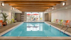 Une piscine dotée d’un plafond en bois, de chaises et offrant une vue sur l’extérieur.