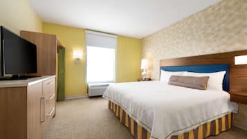 A hotel room with a bed, a television, a desk, and a window with blinds.