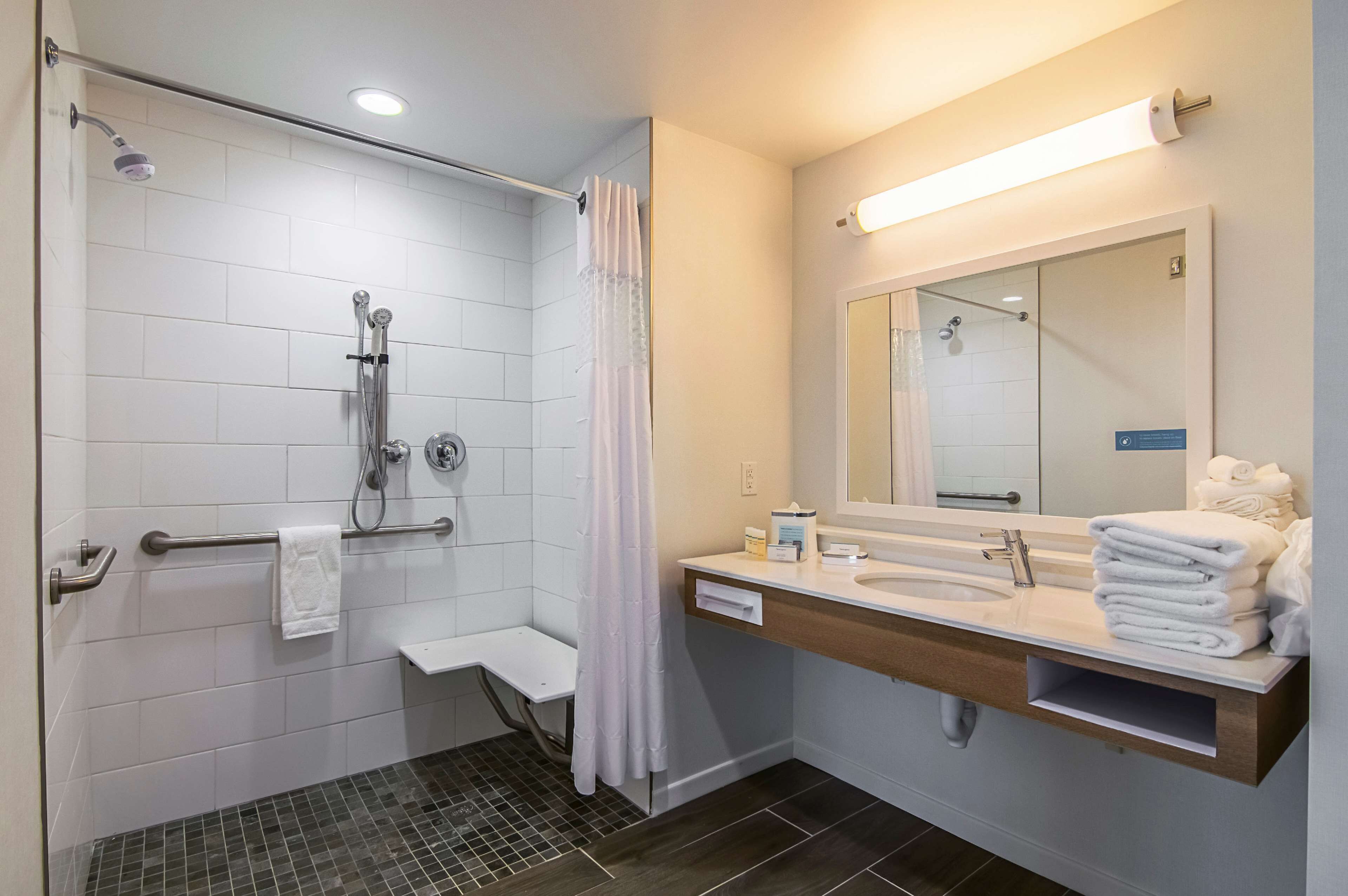 Une salle de bain moderne équipée d’une douche, d’un lavabo, d’un miroir et d’un porte-serviettes.