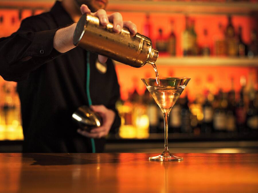 Un barman sirviendo una bebida en una copa de martini.
