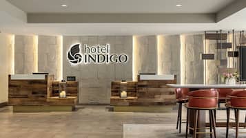 Un moderno vestíbulo de hotel con recepción, zona de bar y asientos.