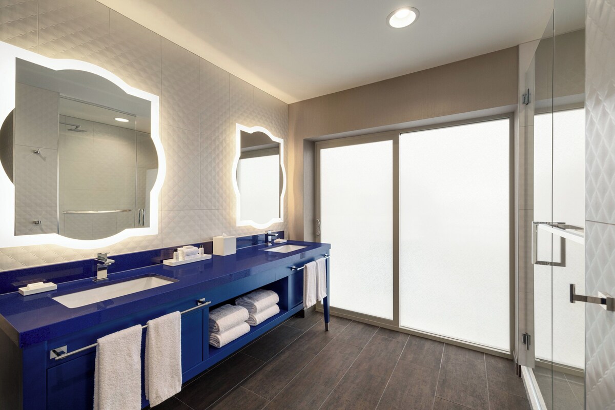 Une salle de bain moderne dotée d’un meuble-lavabo à deux vasques, d’un grand miroir et d’une cabine de douche en verre.