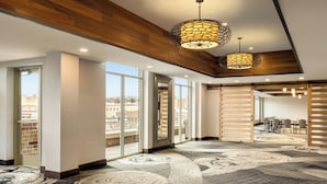 A spacious lobby with large windows, a patterned carpet, and wooden ceiling beams.