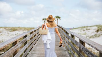 A wooden boardwalk leading to a beach with palm trees in the background.