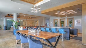 A modern reception area with a wooden reception desk, blue upholstered chairs, and a hanging light fixture.