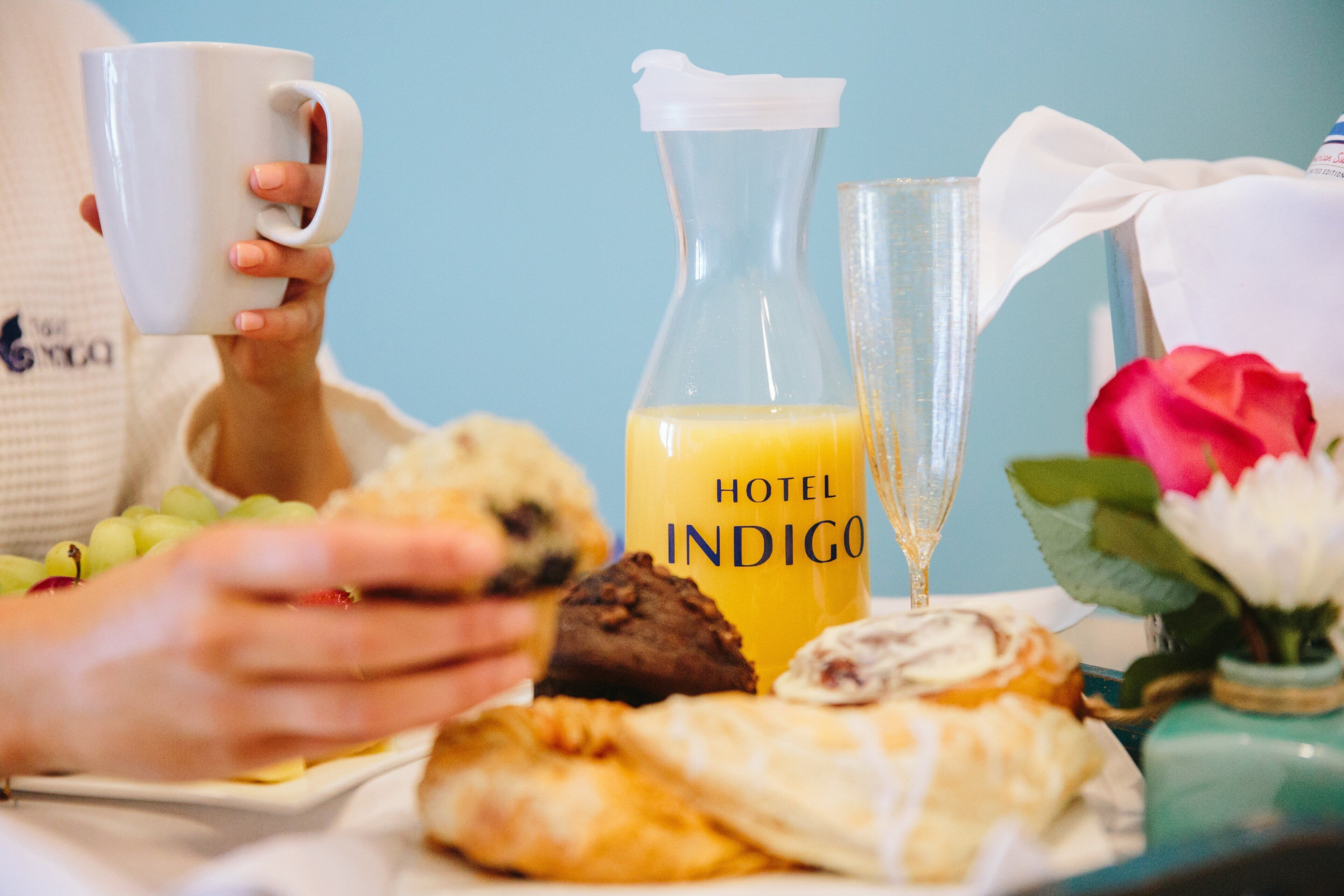 A breakfast setting with a plate of pastries, a glass of orange juice, and a white mug.