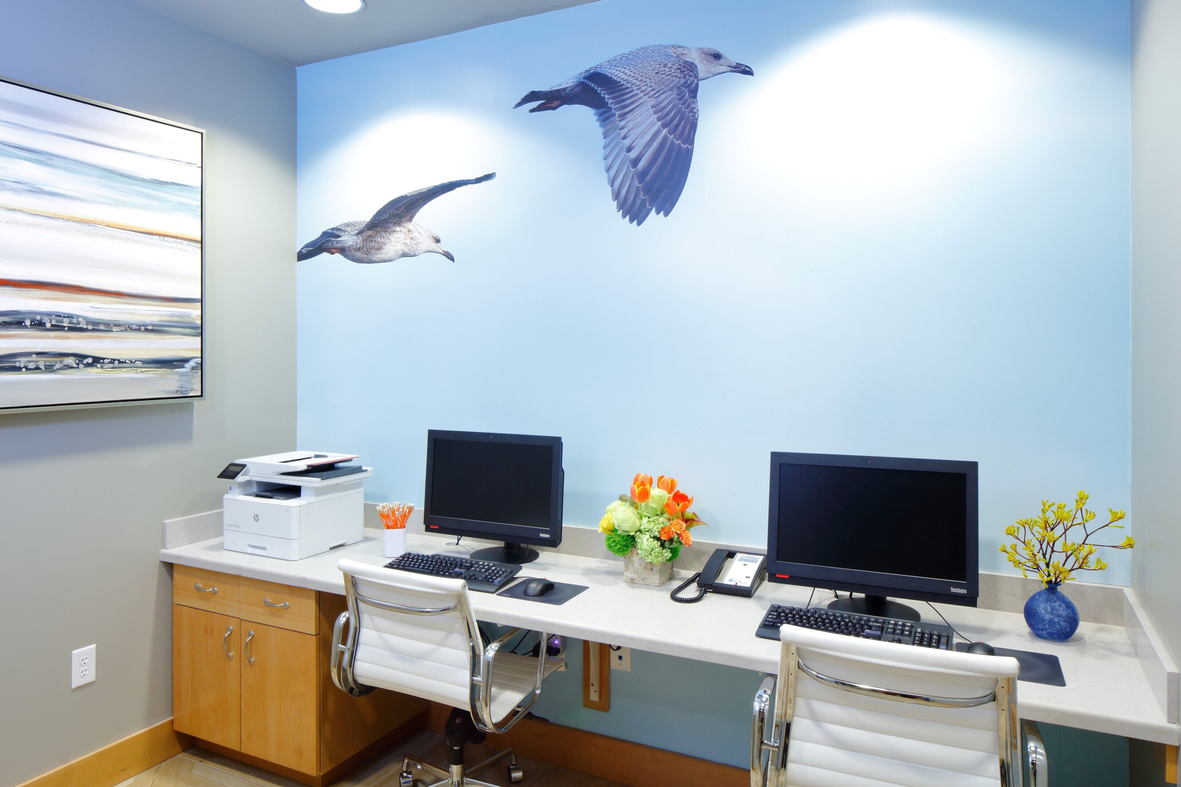 A modern office with two desks, computers, and chairs.