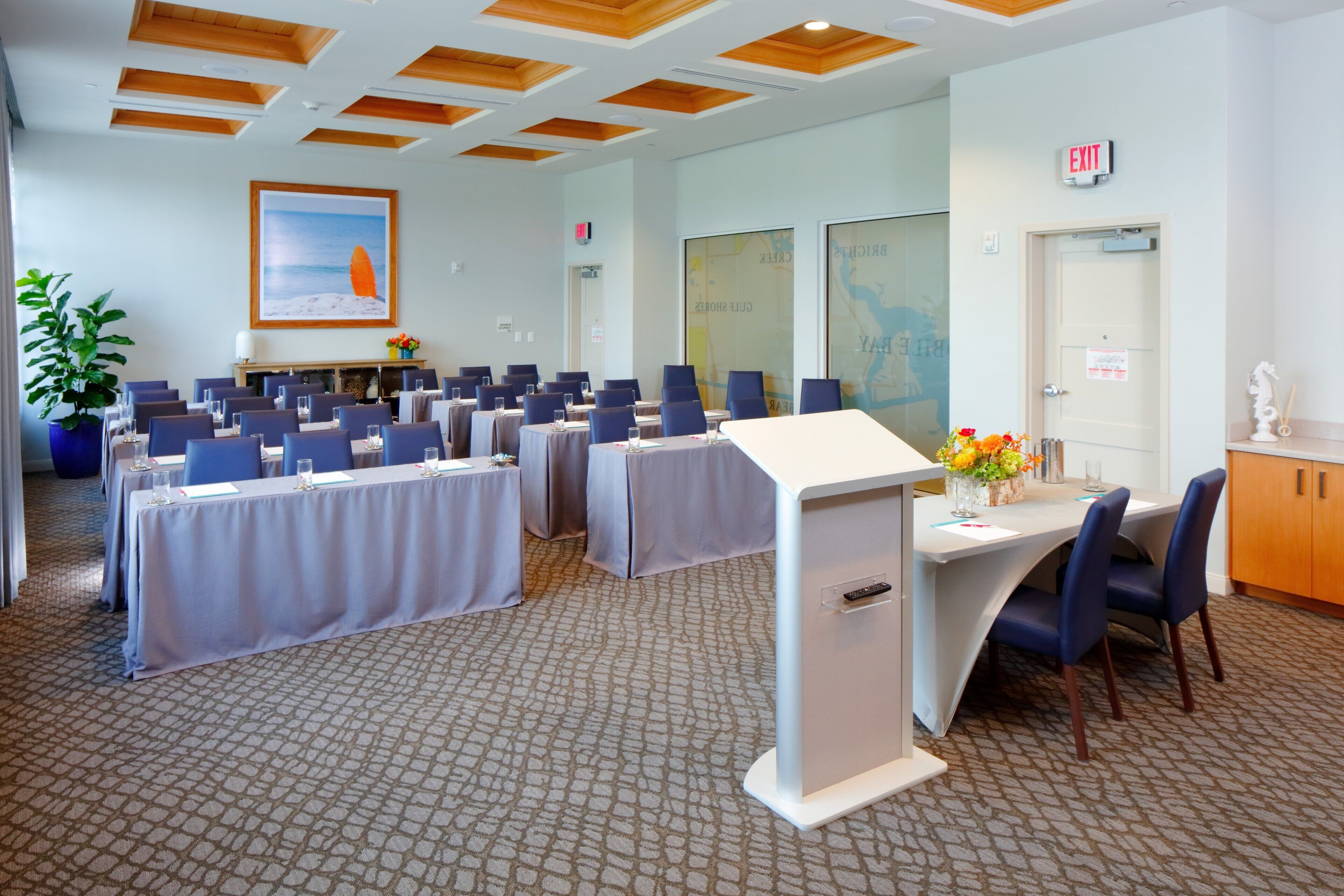 Une salle de conférence équipée de tables et de chaises, d’un tableau blanc et ornée d’un tableau au mur.