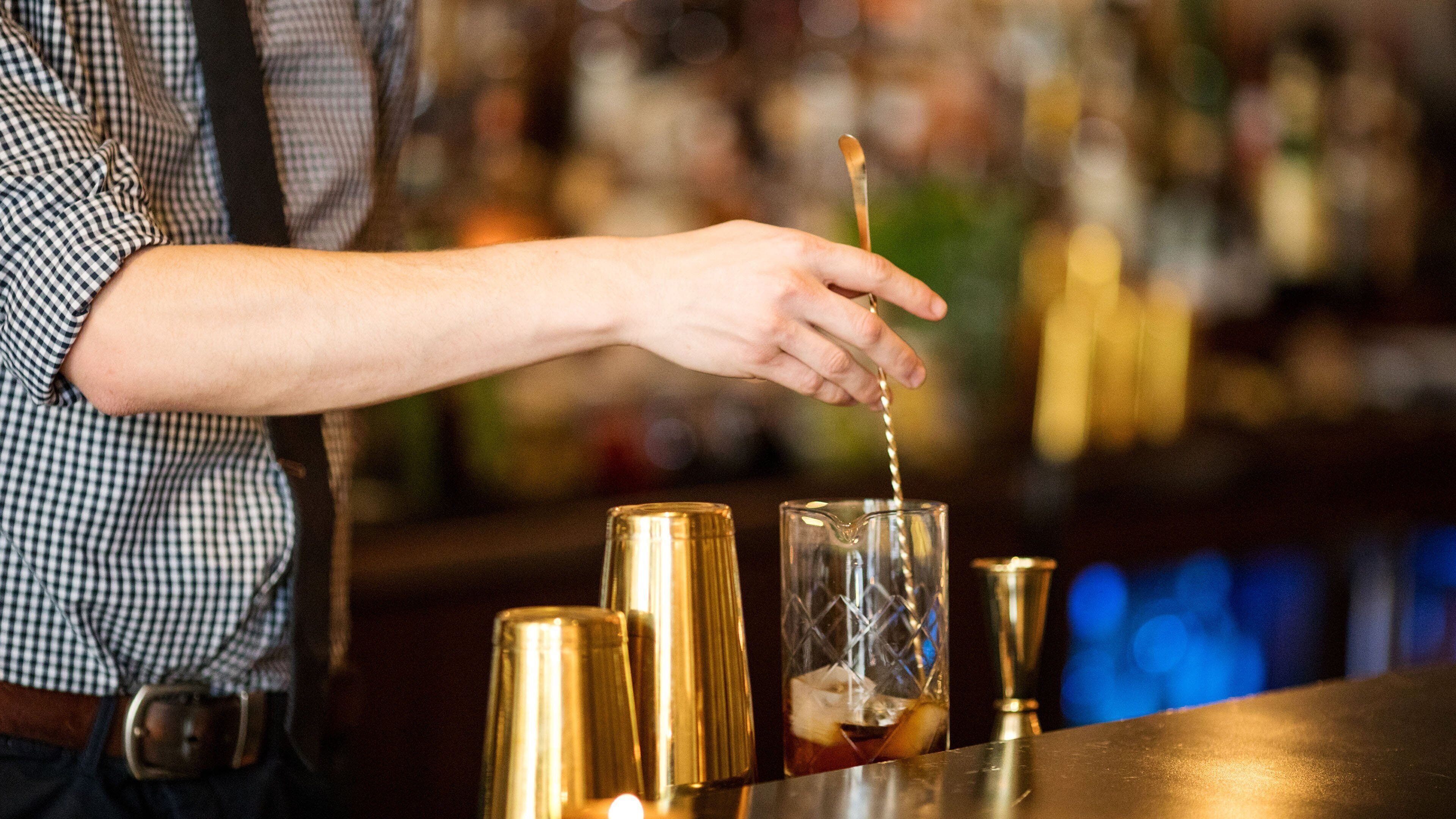 A bartender pouring a drink into a glass.