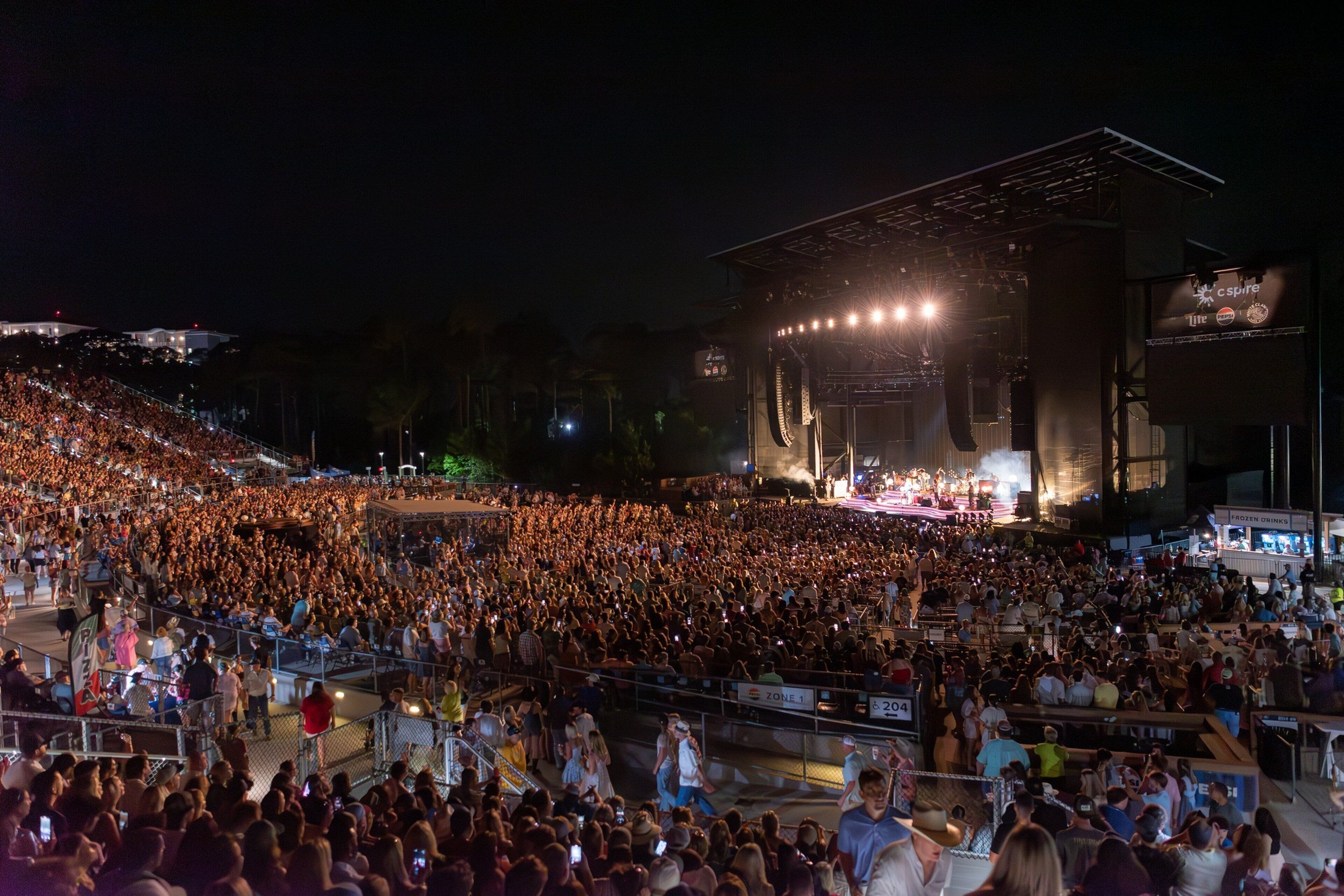 A large outdoor concert venue with tiered seating and a stage.
