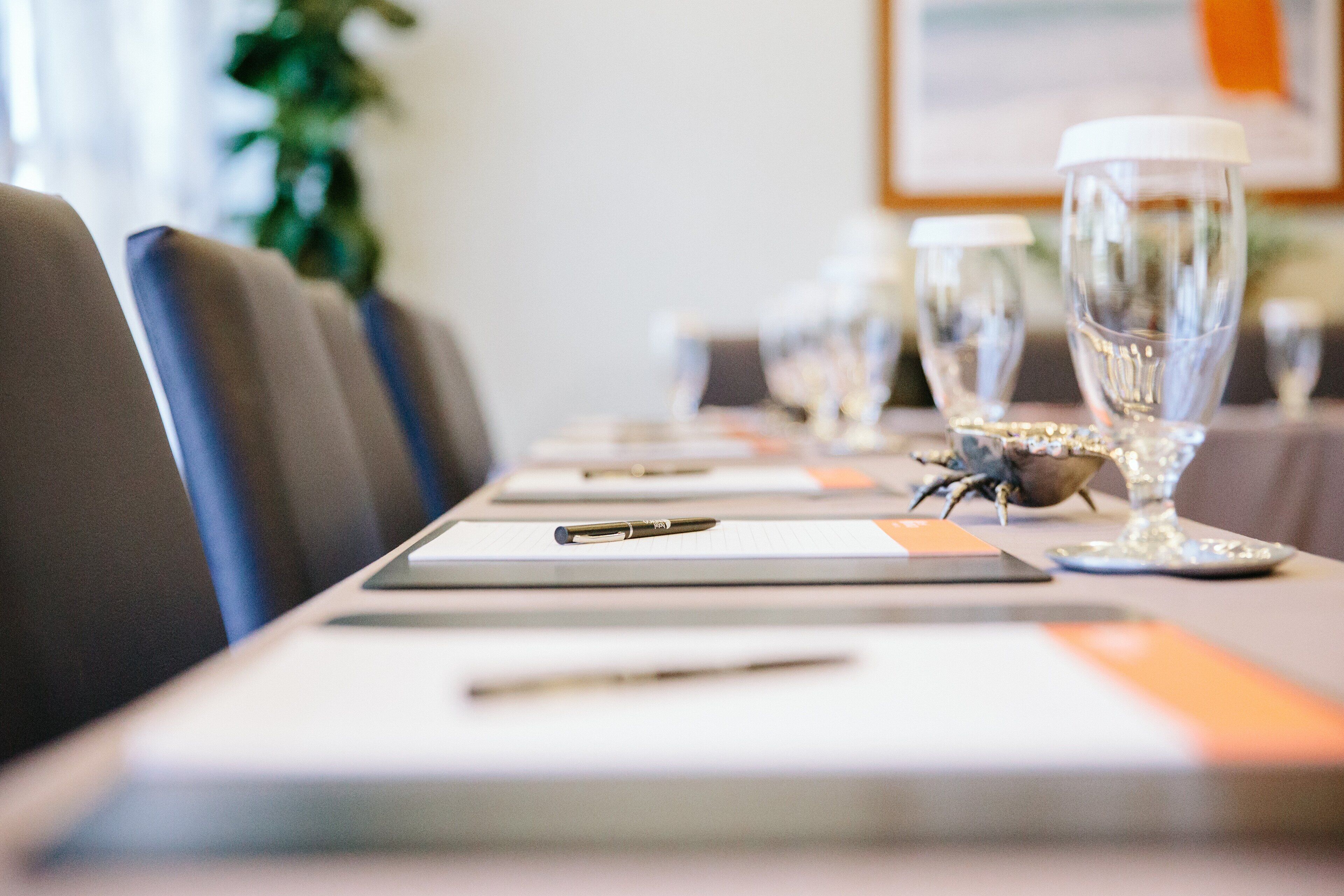 A conference table with place settings, including plates, cutlery, and glasses.