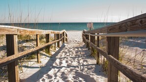 A wooden boardwalk leading to a sandy beach with the ocean in the background.
