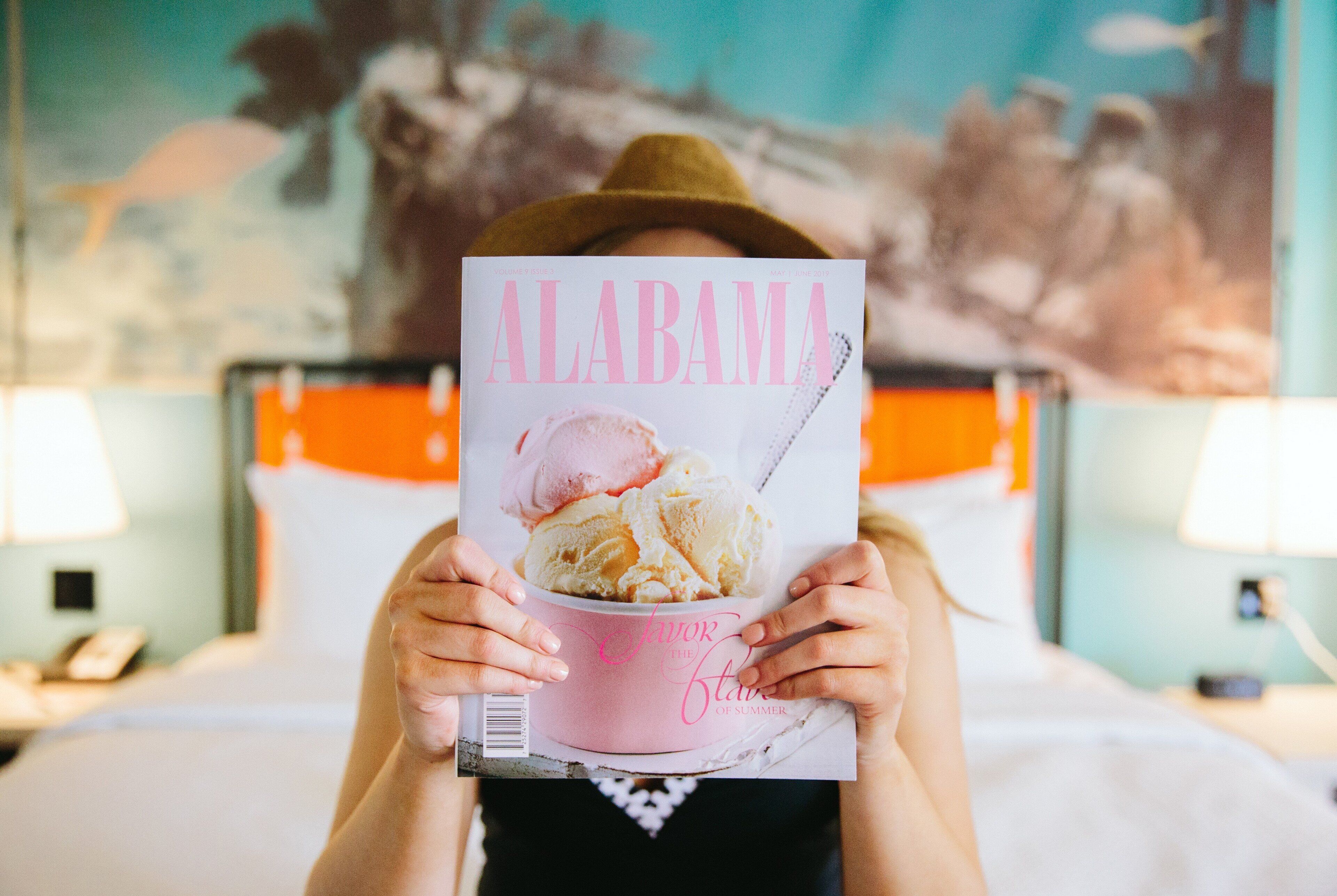 Henkilö pitää kädessään lehteä, jonka kannessa on teksti ’ALABAMA’ ja kuva jäätelöstä.
