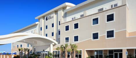 Un hotel de diseño moderno, con techo plano, grandes ventanales y un área de entrada cubierta.
