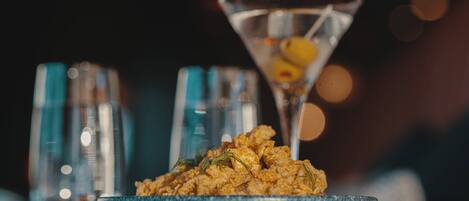 A martini glass with a lemon slice on a blue plate, accompanied by a glass of water and a bottle of olive oil.