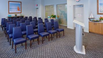 A conference room with rows of blue chairs, a podium, and a map on the wall.
