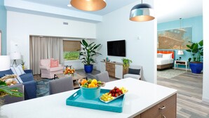 A modern hotel room with a dining area, a living room, and a bedroom.