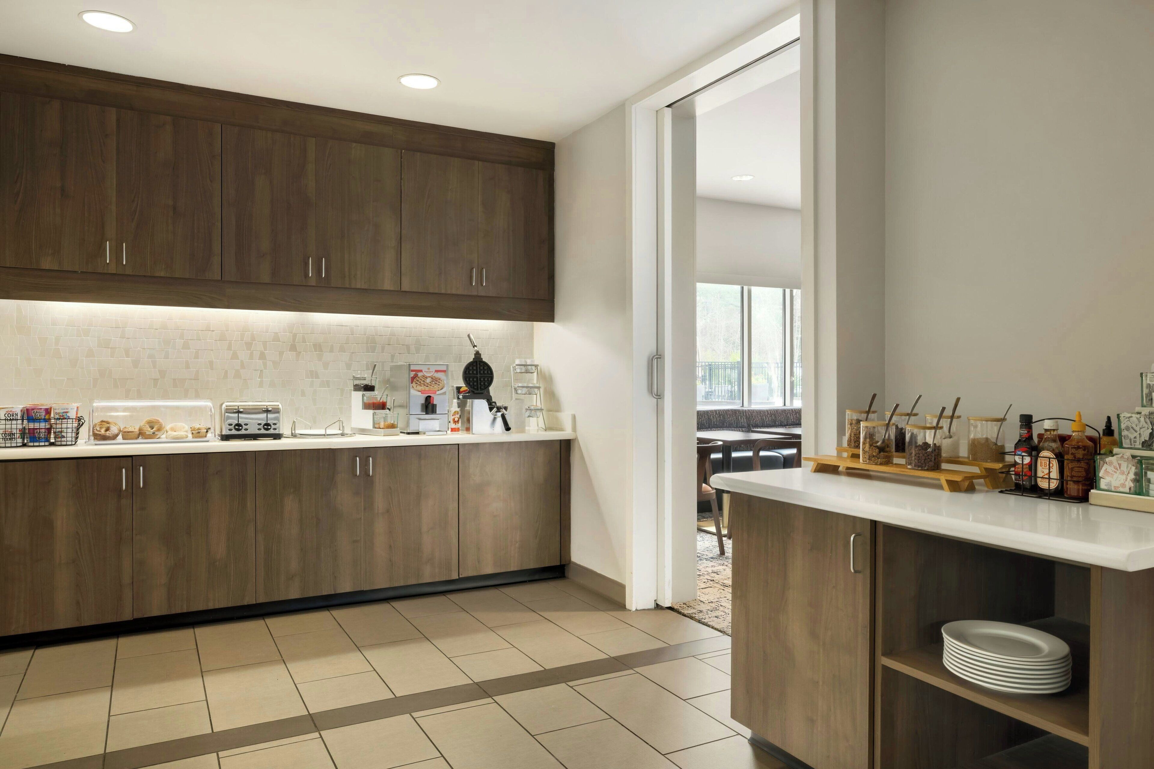 A modern kitchen with wooden cabinets, a white countertop, and a breakfast bar.